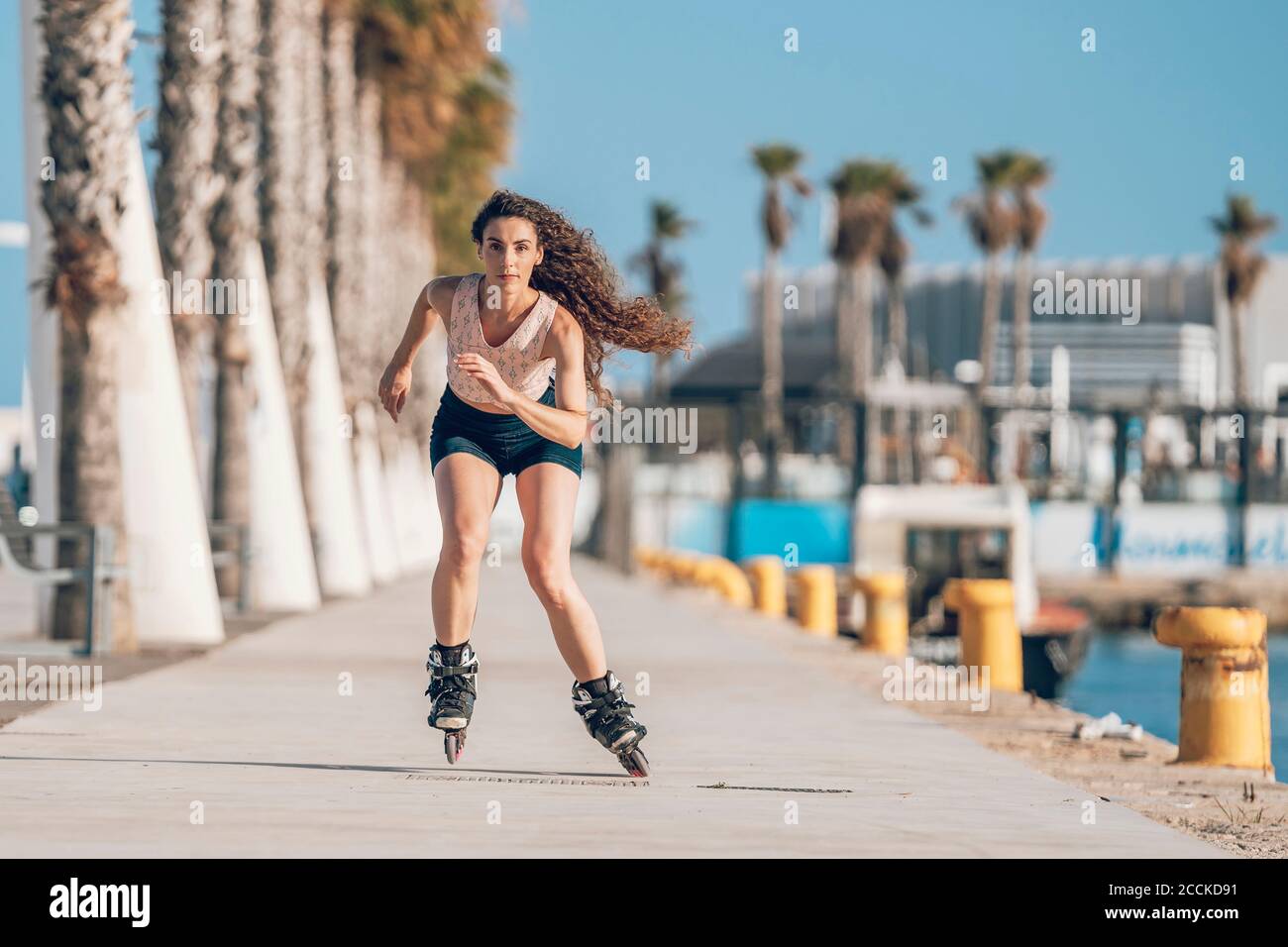 Young woman inline skating on promenade at the coast Stock Photo