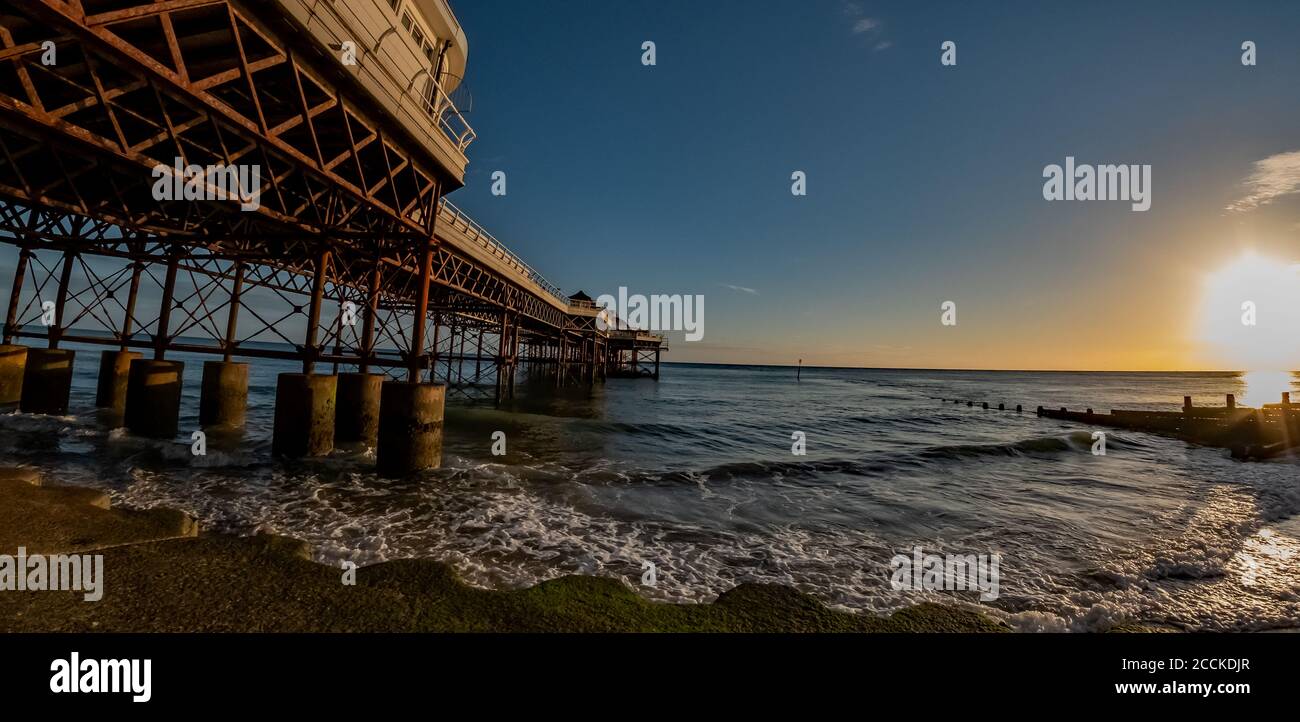 Fisheye view cpatured from the sandy beach next to the Victorian pier in the seside town of Cromer on the North Norfolk coast at sunrise. Intentional Stock Photo