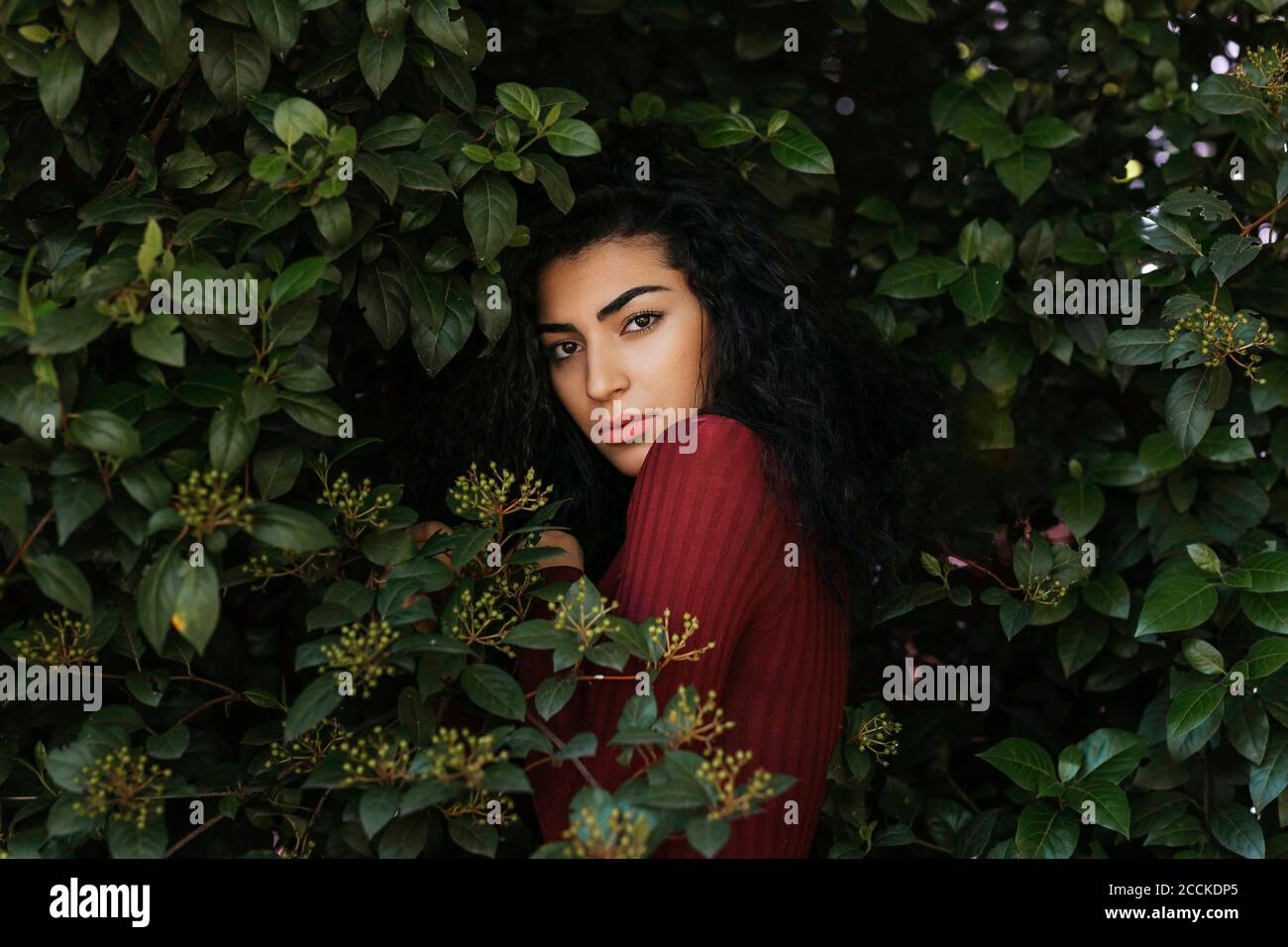 Portrait of young black-haired woman between leaves Stock Photo