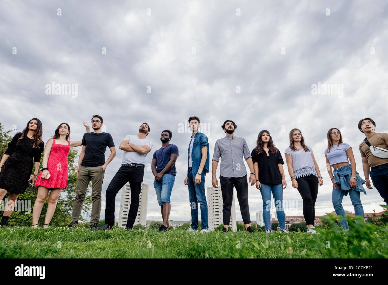 Group of friends standing side by side on grassy land against sky in park Stock Photo