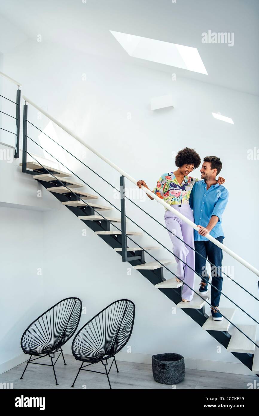 Affectionate couple standing on floating stairs in modern penthouse Stock Photo