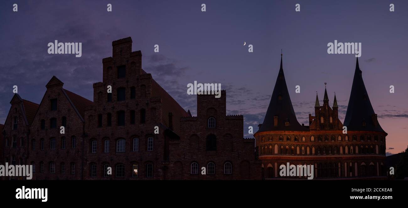 Germany, Schleswig-Holstein, Lubeck, Salzspeicher warehouses and Holsten Gate at night Stock Photo