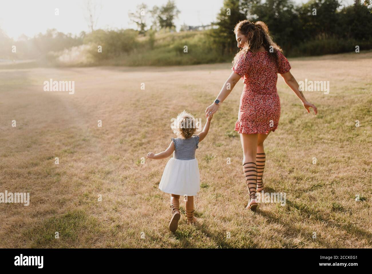 Mother and daughter walking on a meadow in backlight Stock Photo