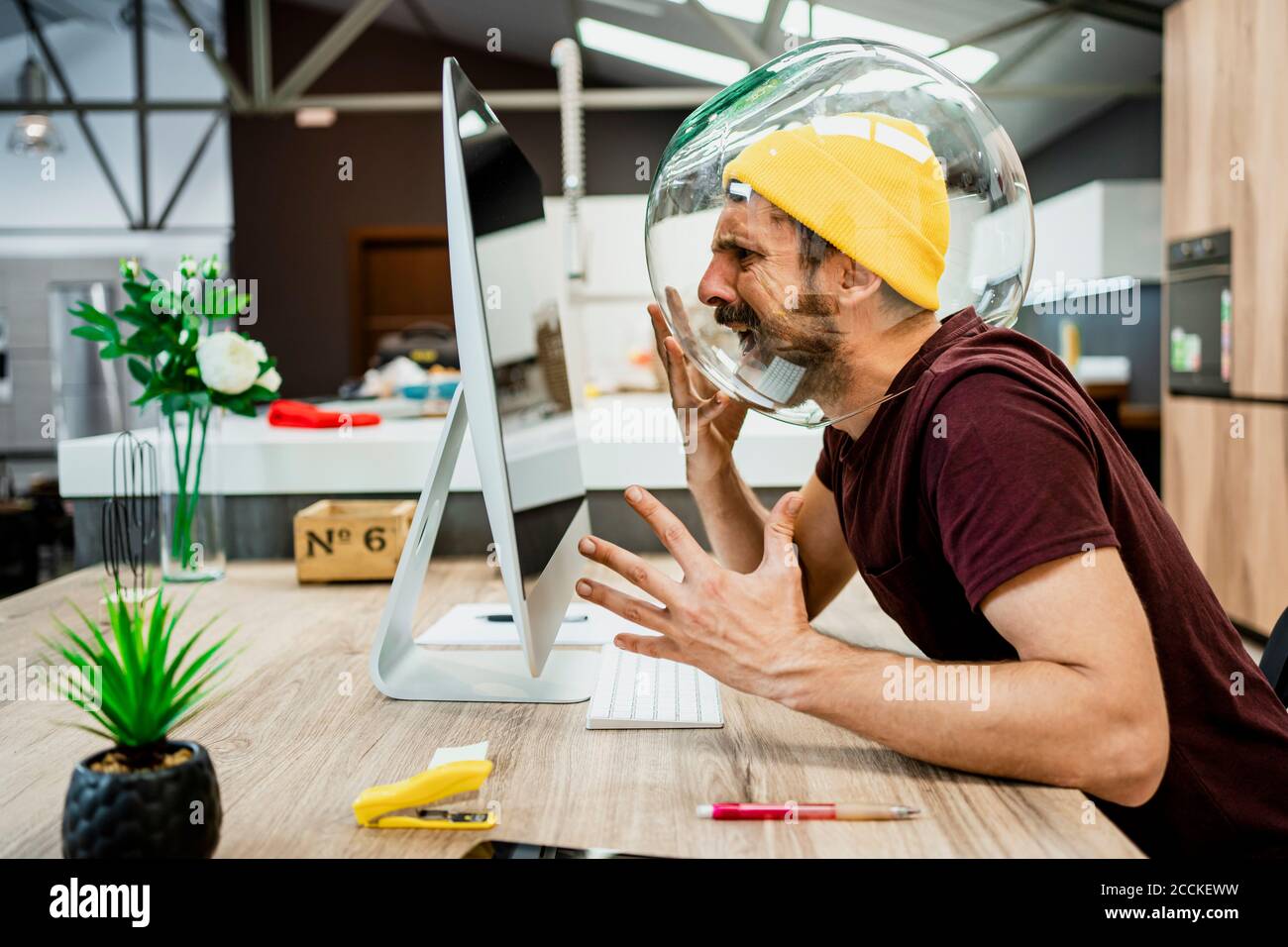 Frustrated businessman with fishbowl in head screaming while using
