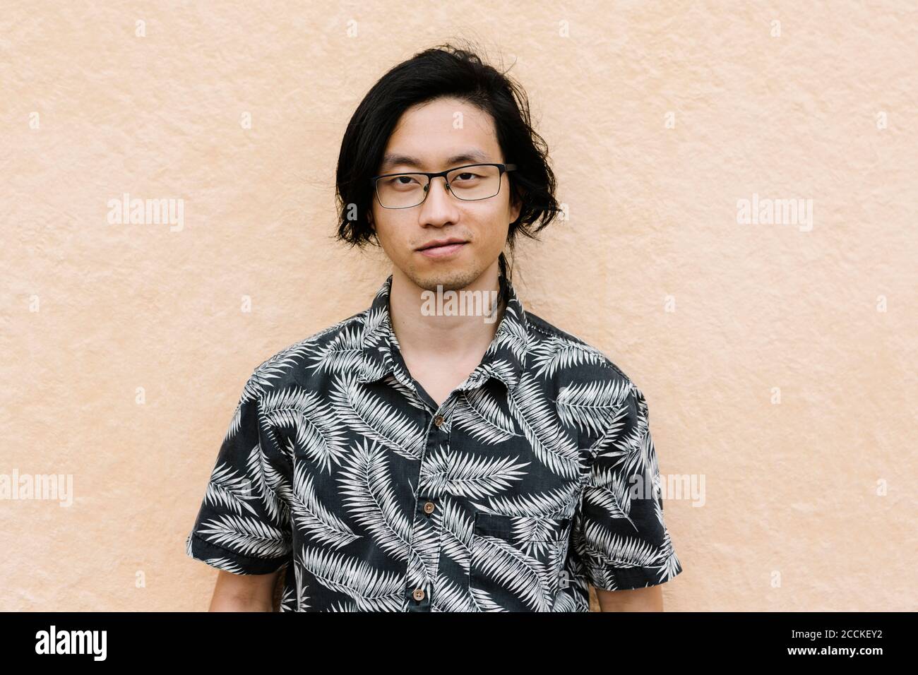 Confident young man wearing eyeglasses standing against wall in city Stock Photo
