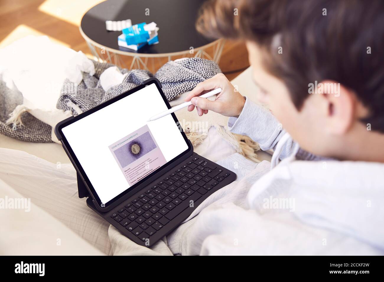 Close-up of young man doing research over digital tablet on sofa at home Stock Photo