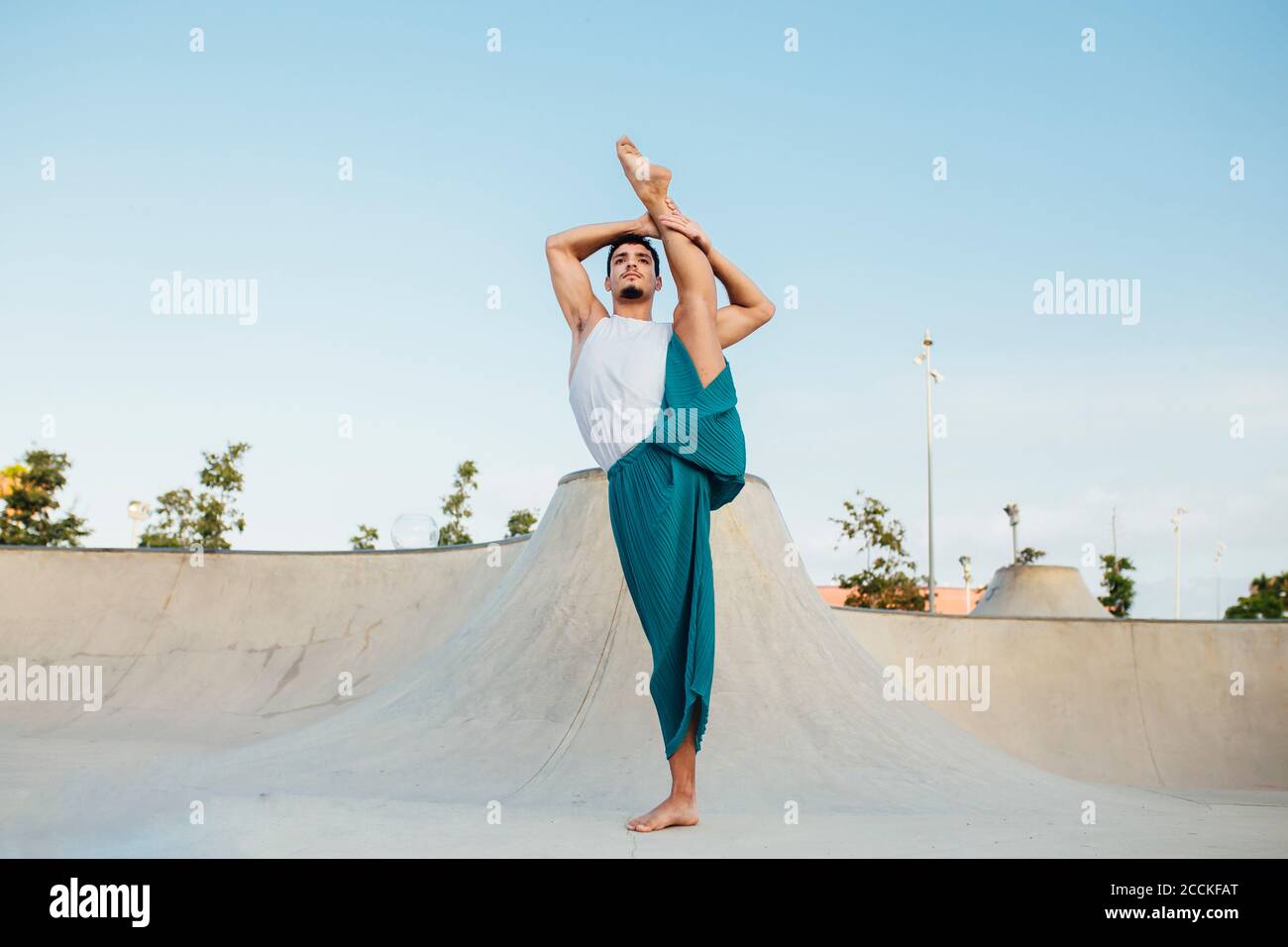Confident man splitting leg while practicing rhythmic gymnastics against clear sky Stock Photo