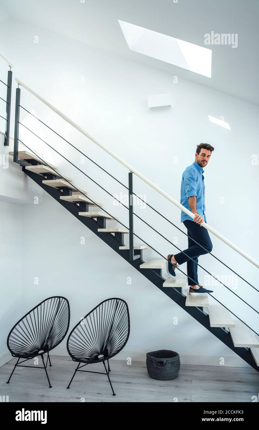 Mid adult man moving down floating stairs in modern penthouse Stock Photo