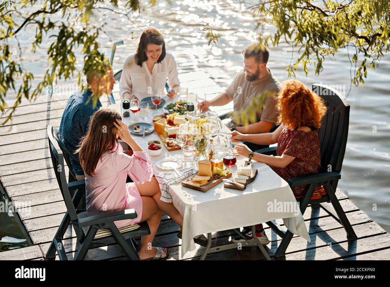 Friends having dinner on jetty at a lake Stock Photo