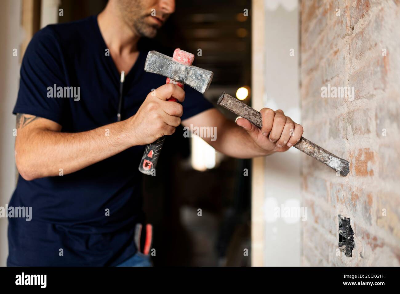 Construction worker using hammer and chisel at a brick wall Stock Photo
