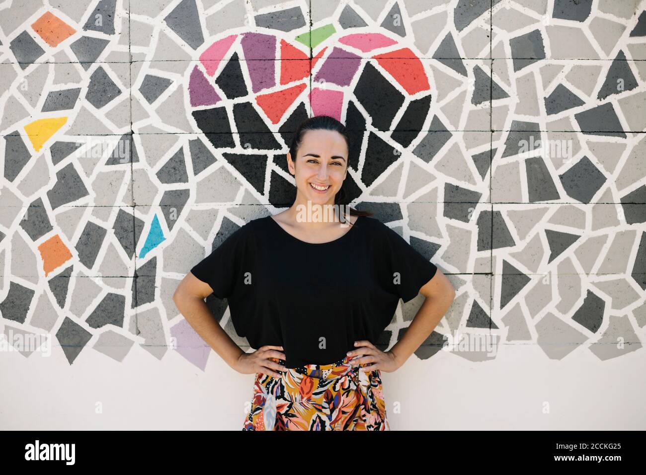 Portrait of smiling woman in front of colorful wall Stock Photo - Alamy