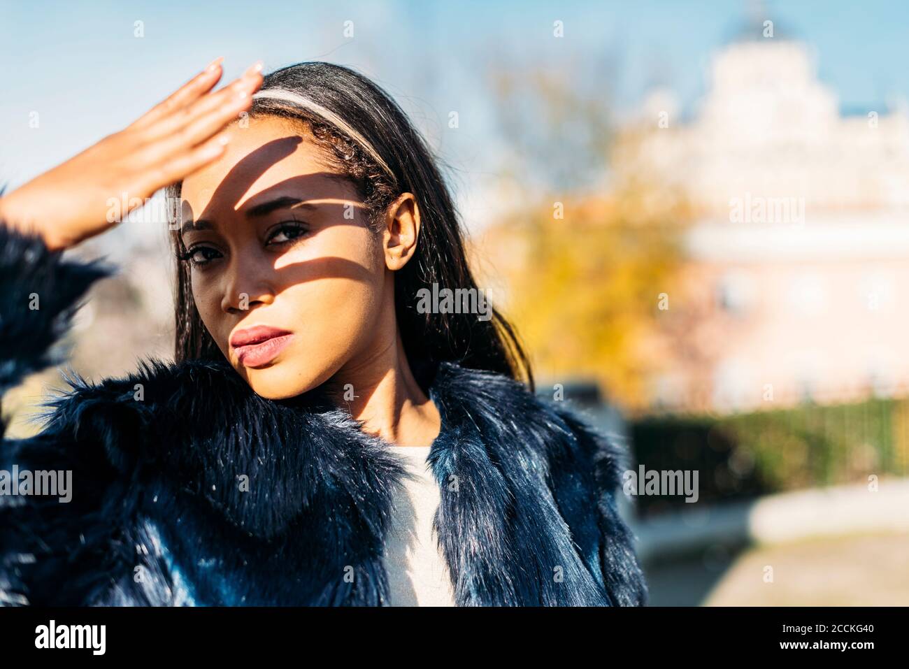 Woman protecting face from sunlight with hand outdoors Stock Photo