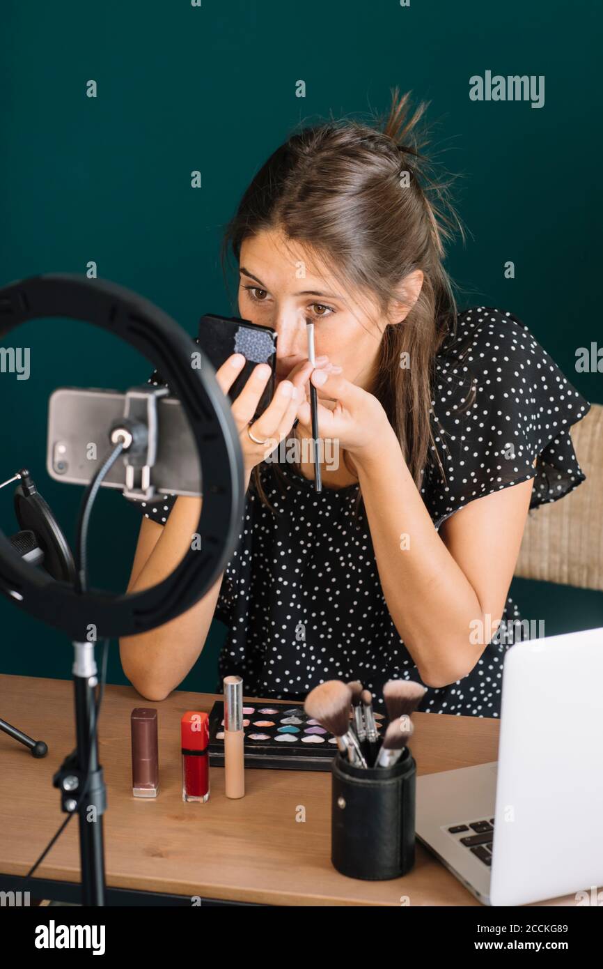 Young woman making a makeup video tutorial applying mascara Stock Photo