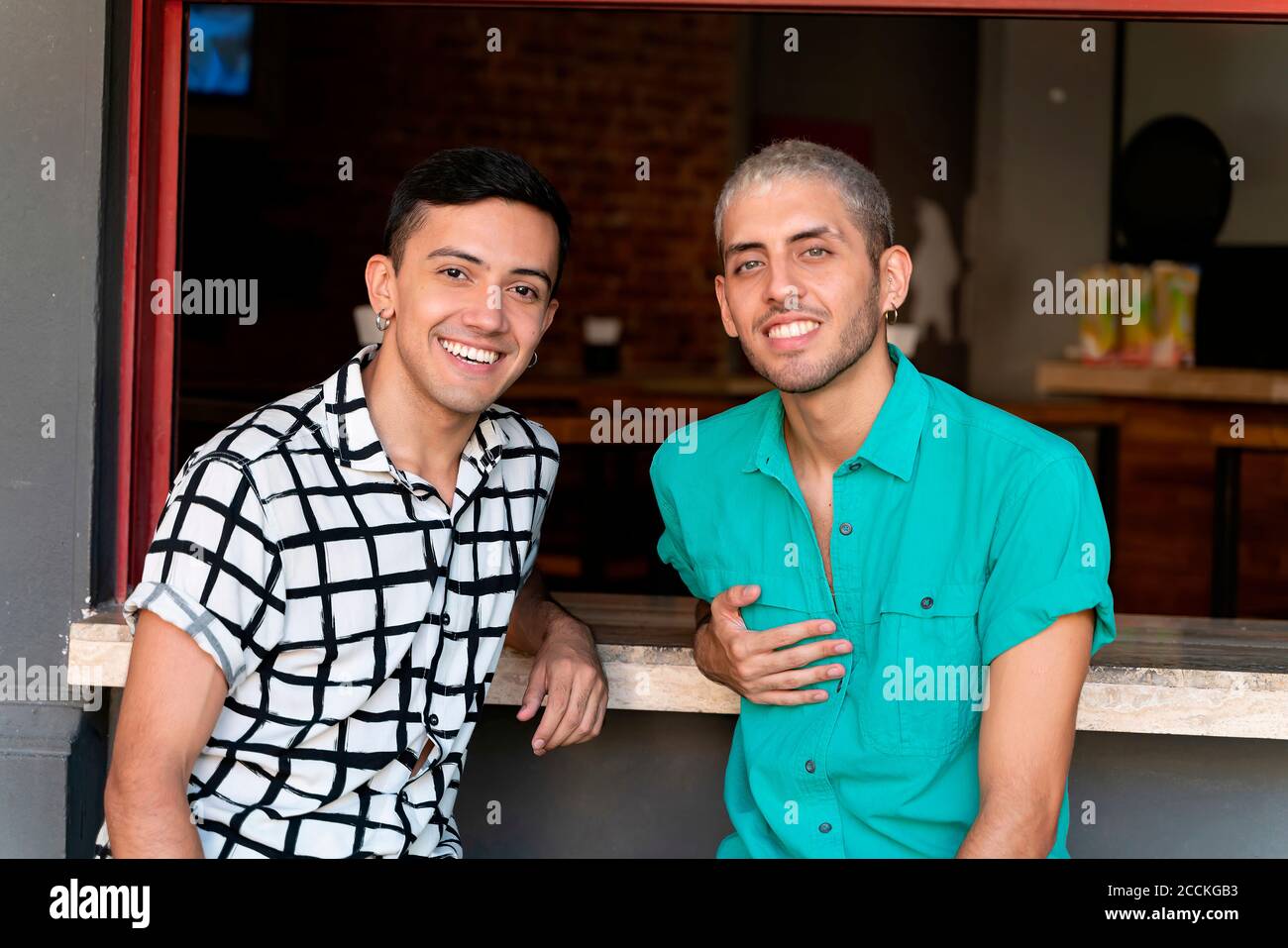 Friends smiling while sitting at bar counter of restaurant Stock Photo