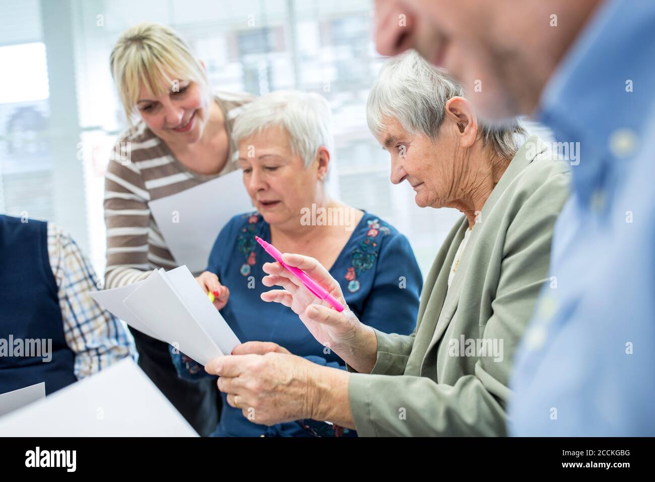 Seniors in therapy group in retirement home writing down notes on sheets of paper Stock Photo