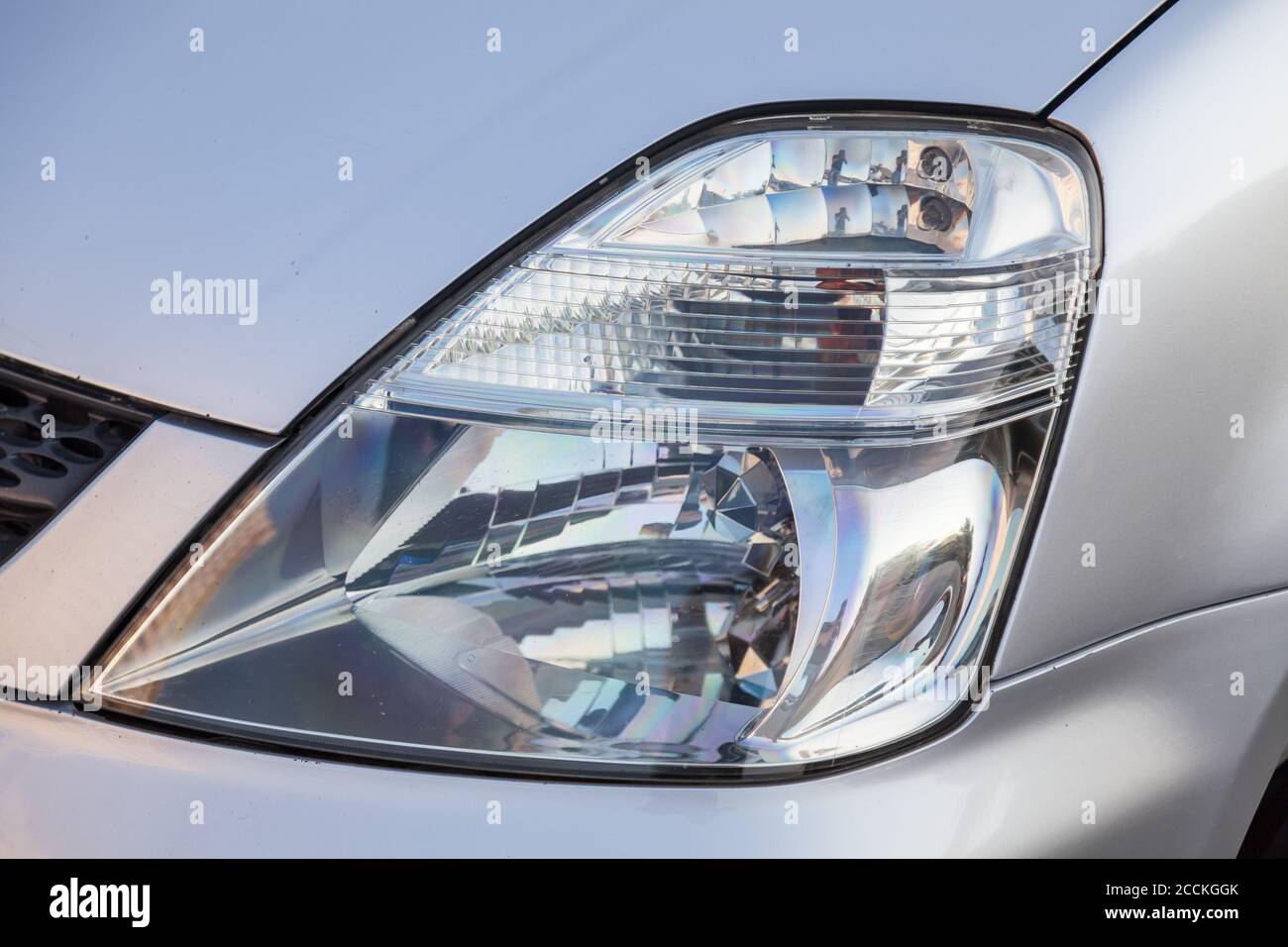 Close-up of the front glass transparent headlight of a Japanese car in silvery color after being replaced in a car service after an accident. Stock Photo