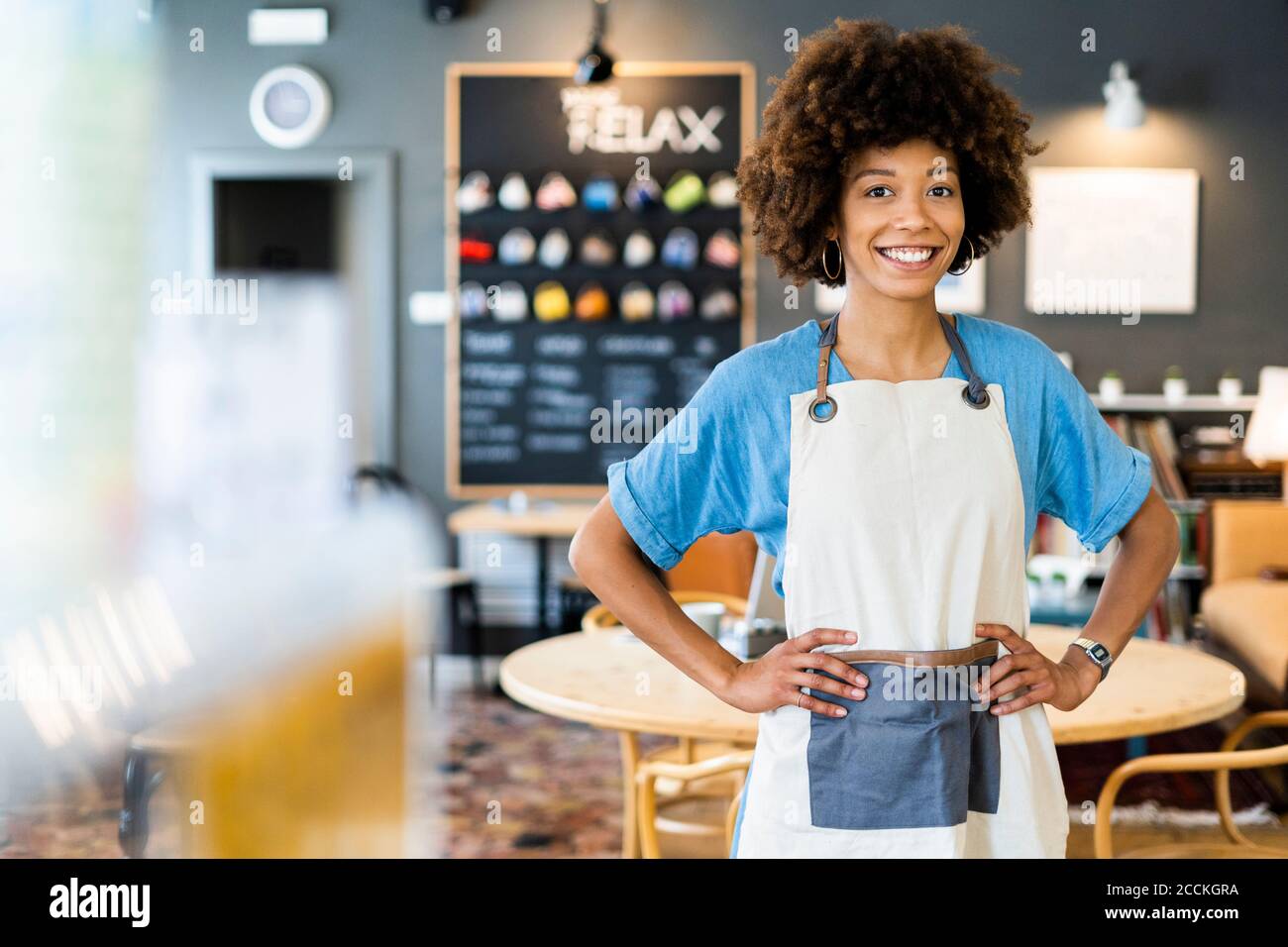 Confident female owner standing with hands on hips at coffee shop Stock Photo