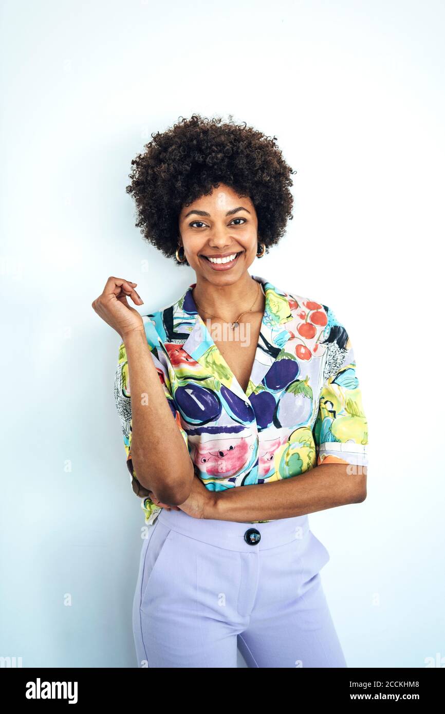 Happy mid adult woman with afro hairstyle standing against white background Stock Photo