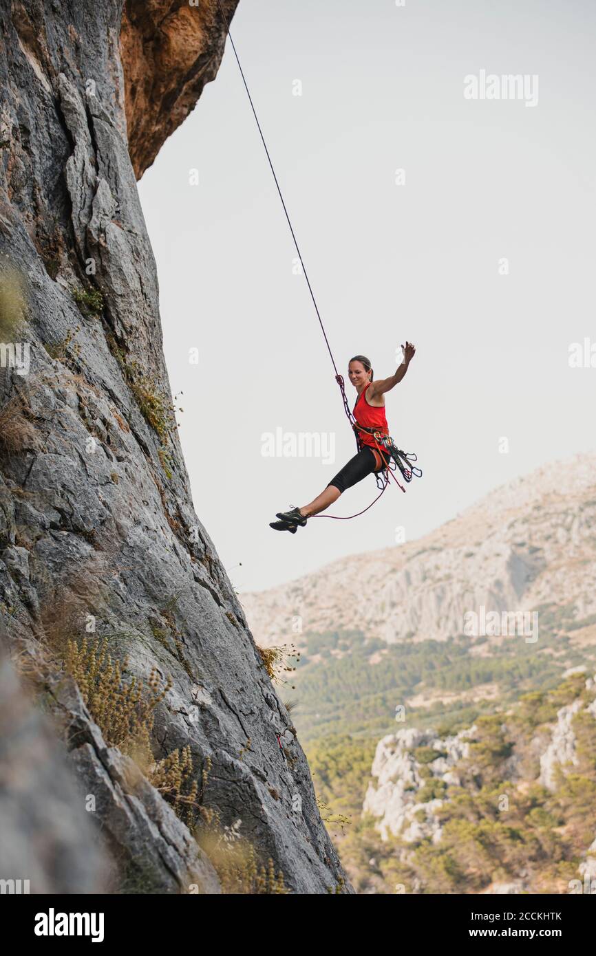 Carefree female rock climber rappelling on rocky mountain Stock Photo ...