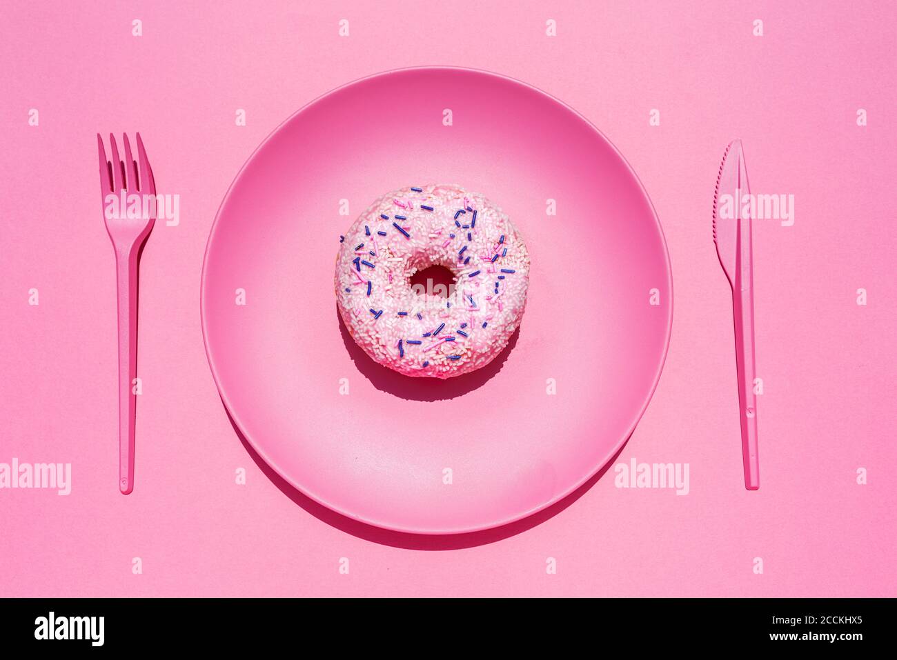 Studio shot of plastic cutlery and plate with sweet doughnut Stock Photo