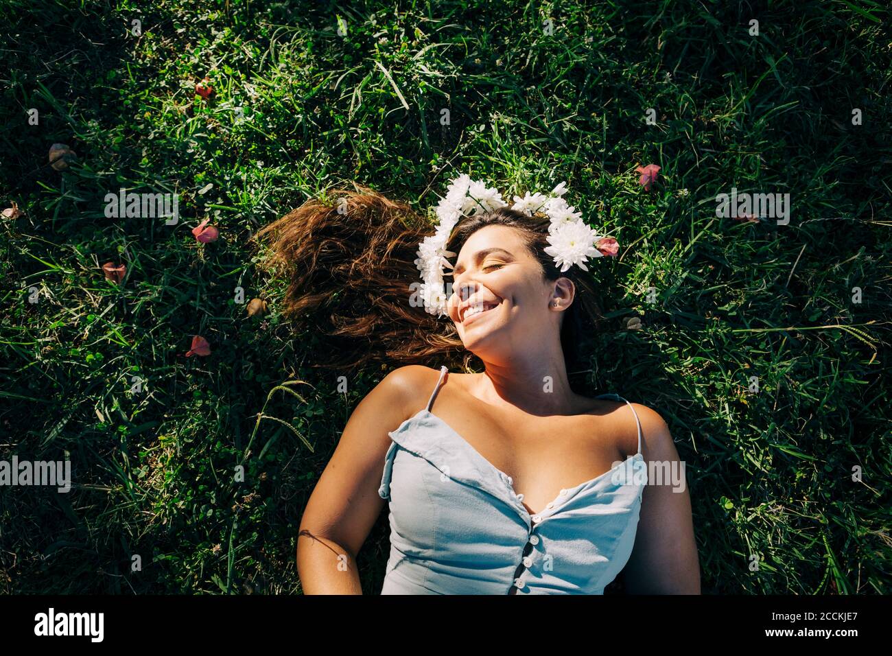 Young woman with eyes closed relaxing on grassy land in park during ...