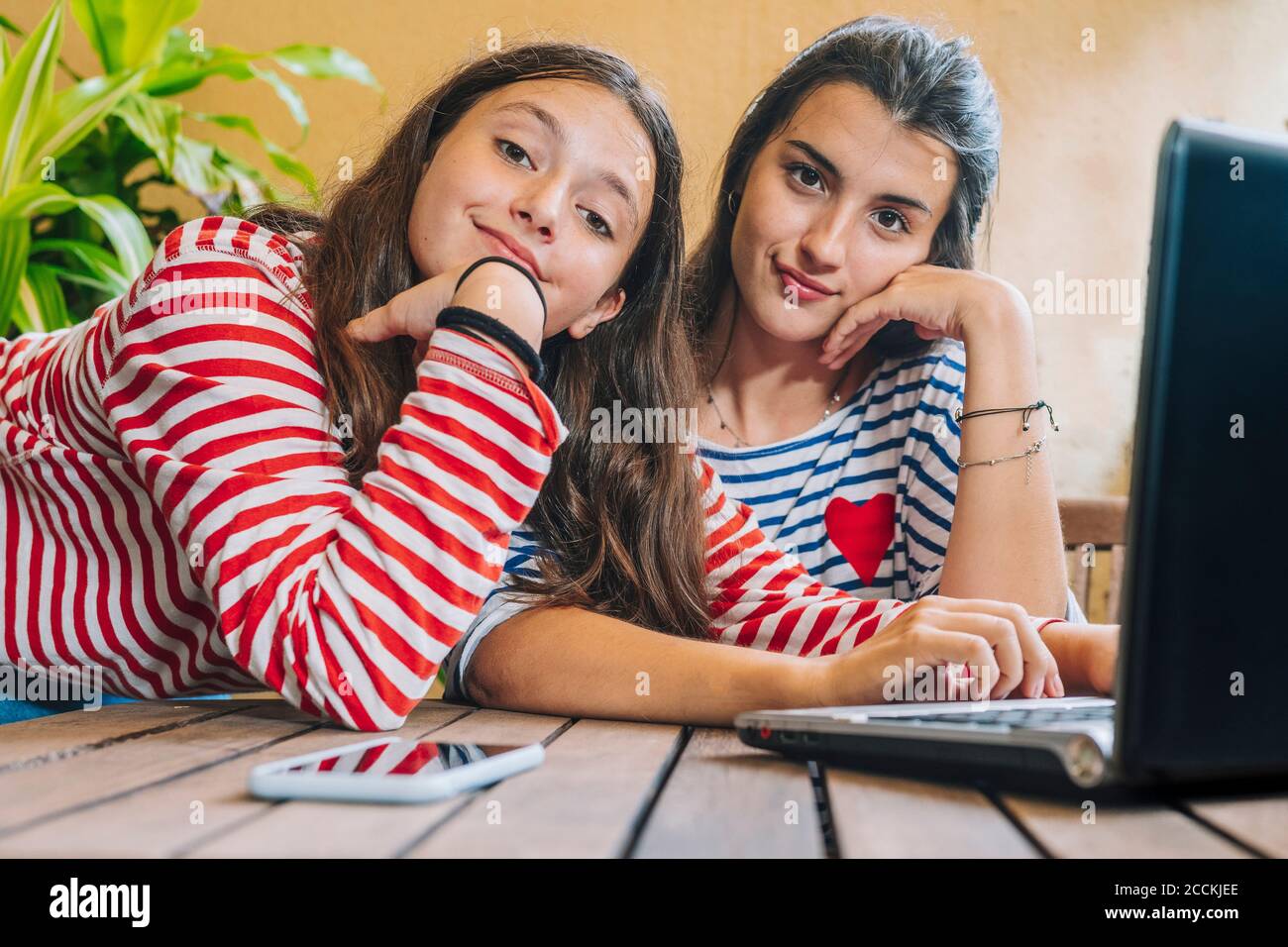Sisters using laptop on table at home Stock Photo
