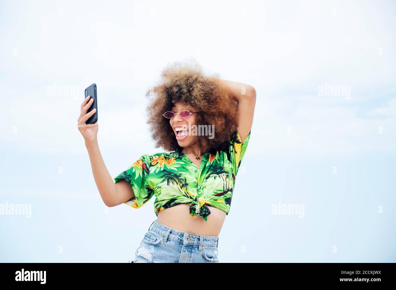 Portrait of laughing young woman taking selfie with smartphone hi-res ...