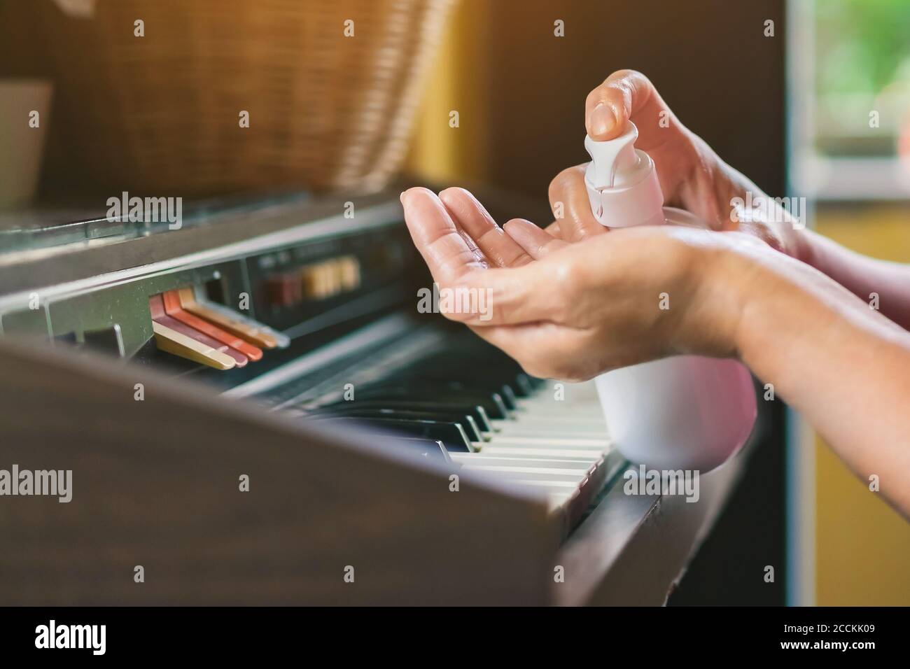 Hands of woman pressed a bottle of alcohol gel to wash her hands and kill the coronavirus (Covid-19) before playing with old organ in her home.New nor Stock Photo
