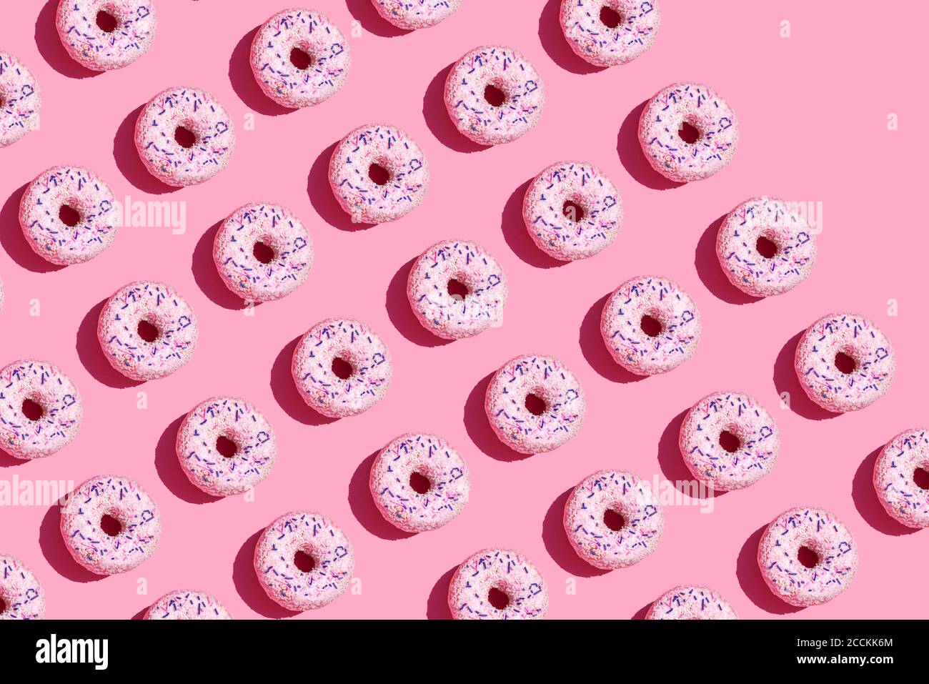 Pattern of sweet doughnuts against pink background Stock Photo
