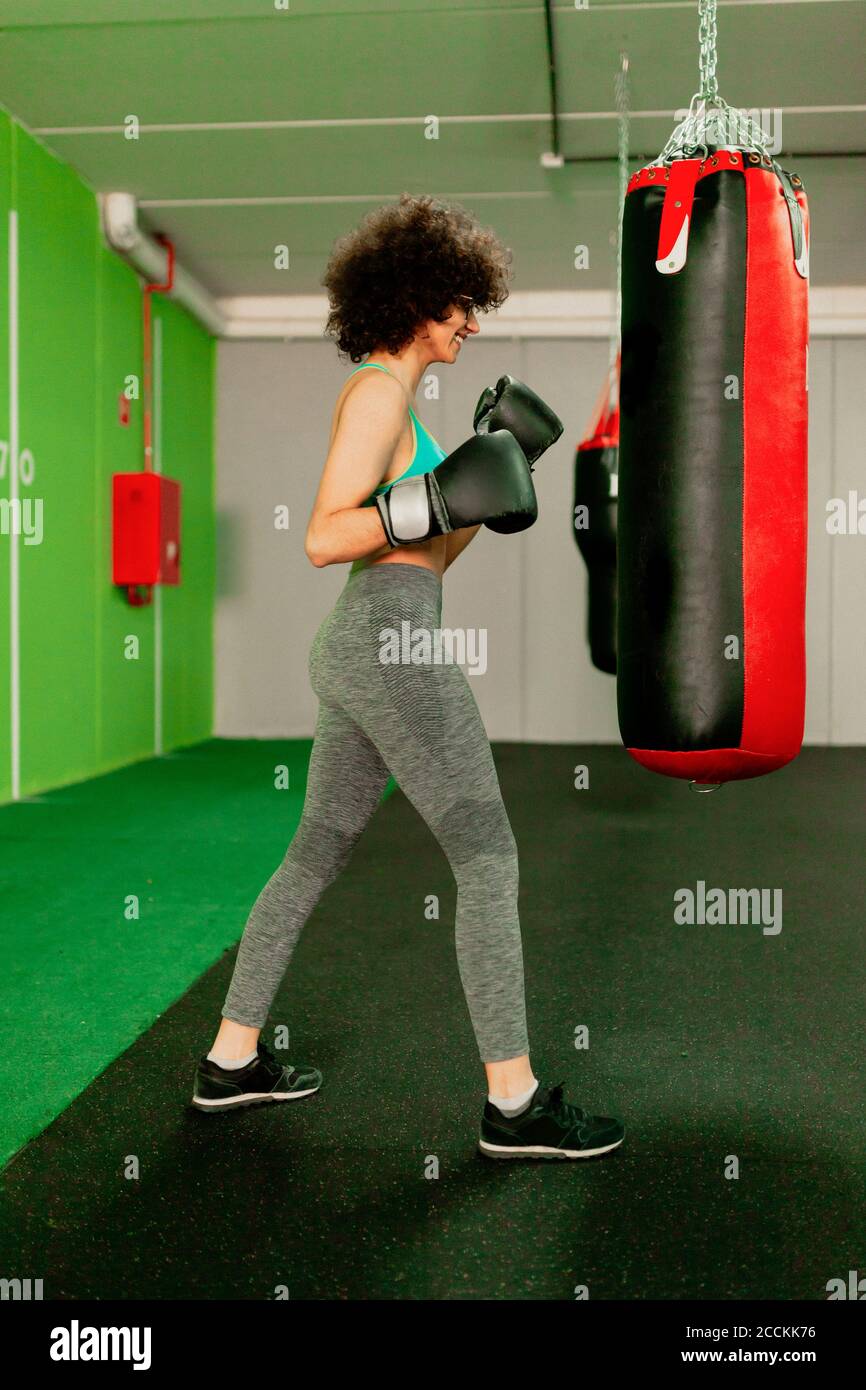 Female boxer practicing with punching bag in health club Stock Photo