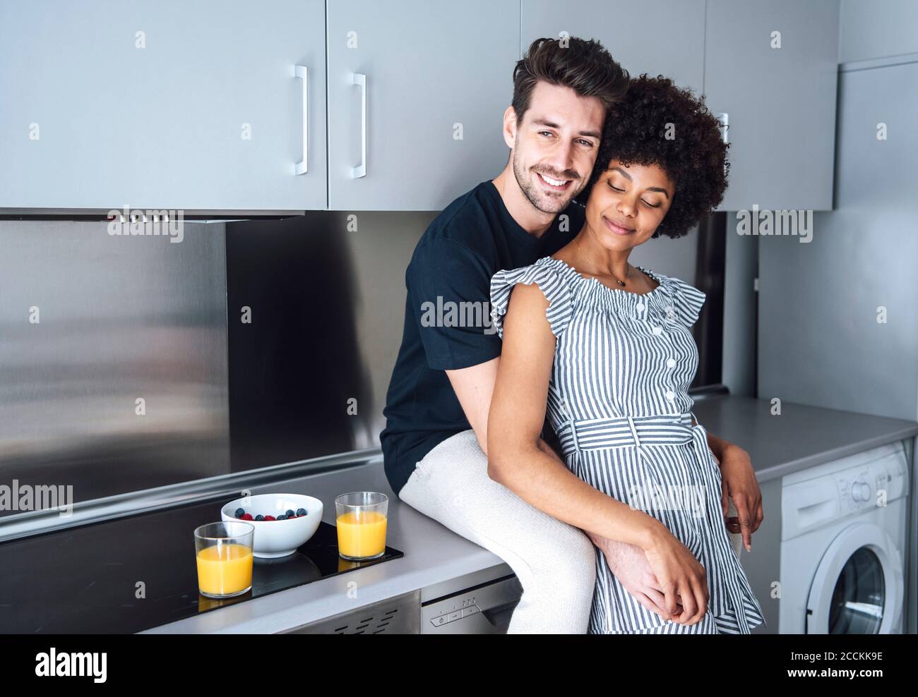 Affectionate multi-ethnic couple in modern kitchen of penthouse Stock Photo