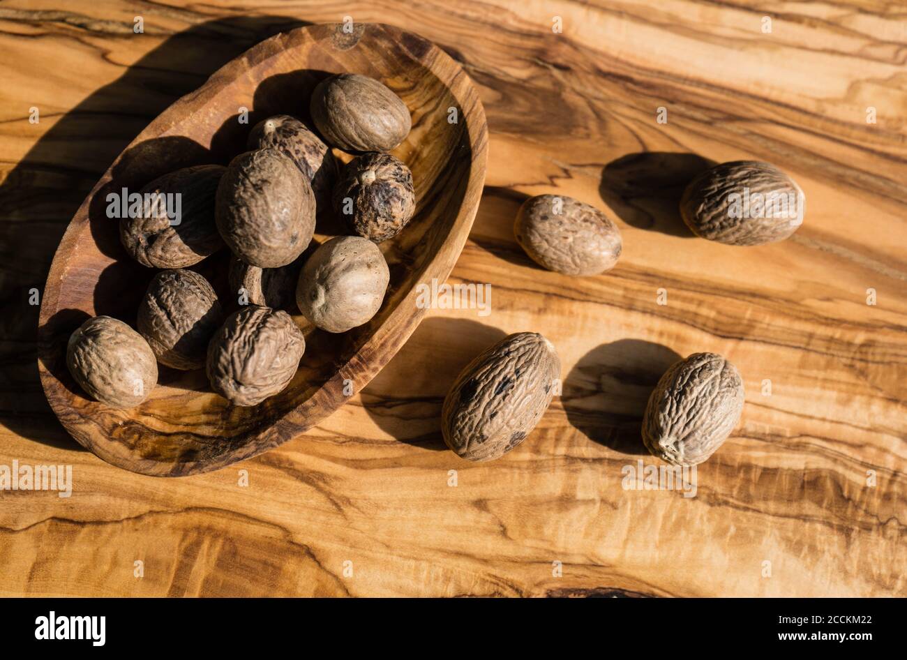 dried brown nutmeg nuts on olive wood Stock Photo Alamy