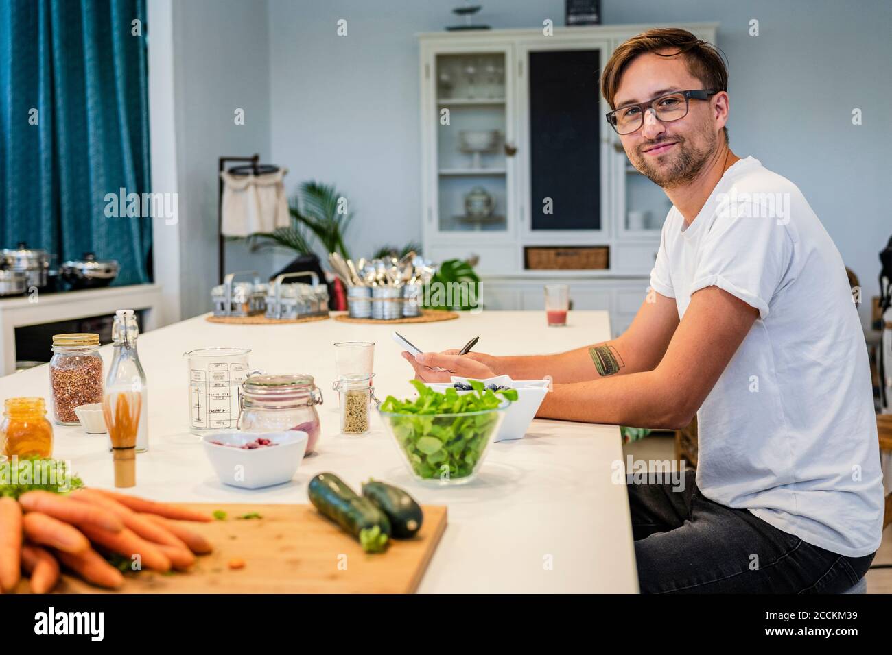 Smiling male student sitting at kitchen island in cooking school Stock Photo