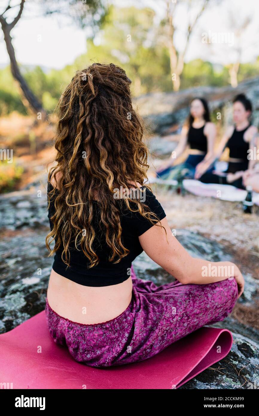 Yoga instructor practicing concentration with females in forest Stock Photo