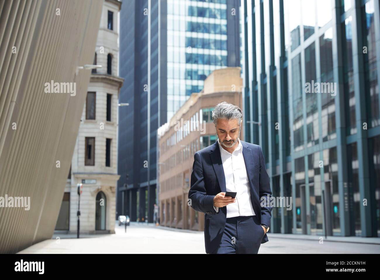Businessman texting through mobile phone in city Stock Photo