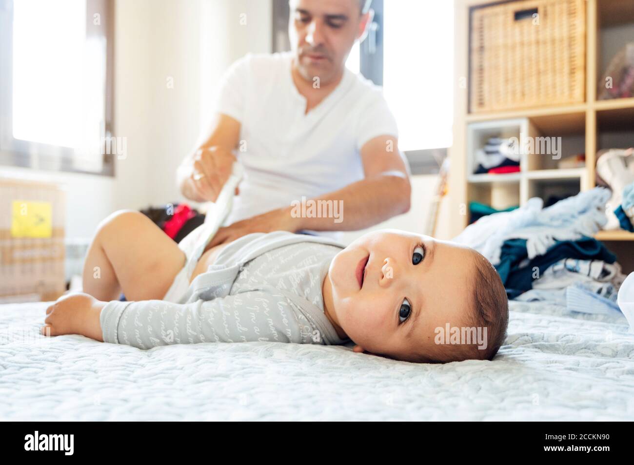 Father with baby boy lying on bed, changing diapers Stock Photo