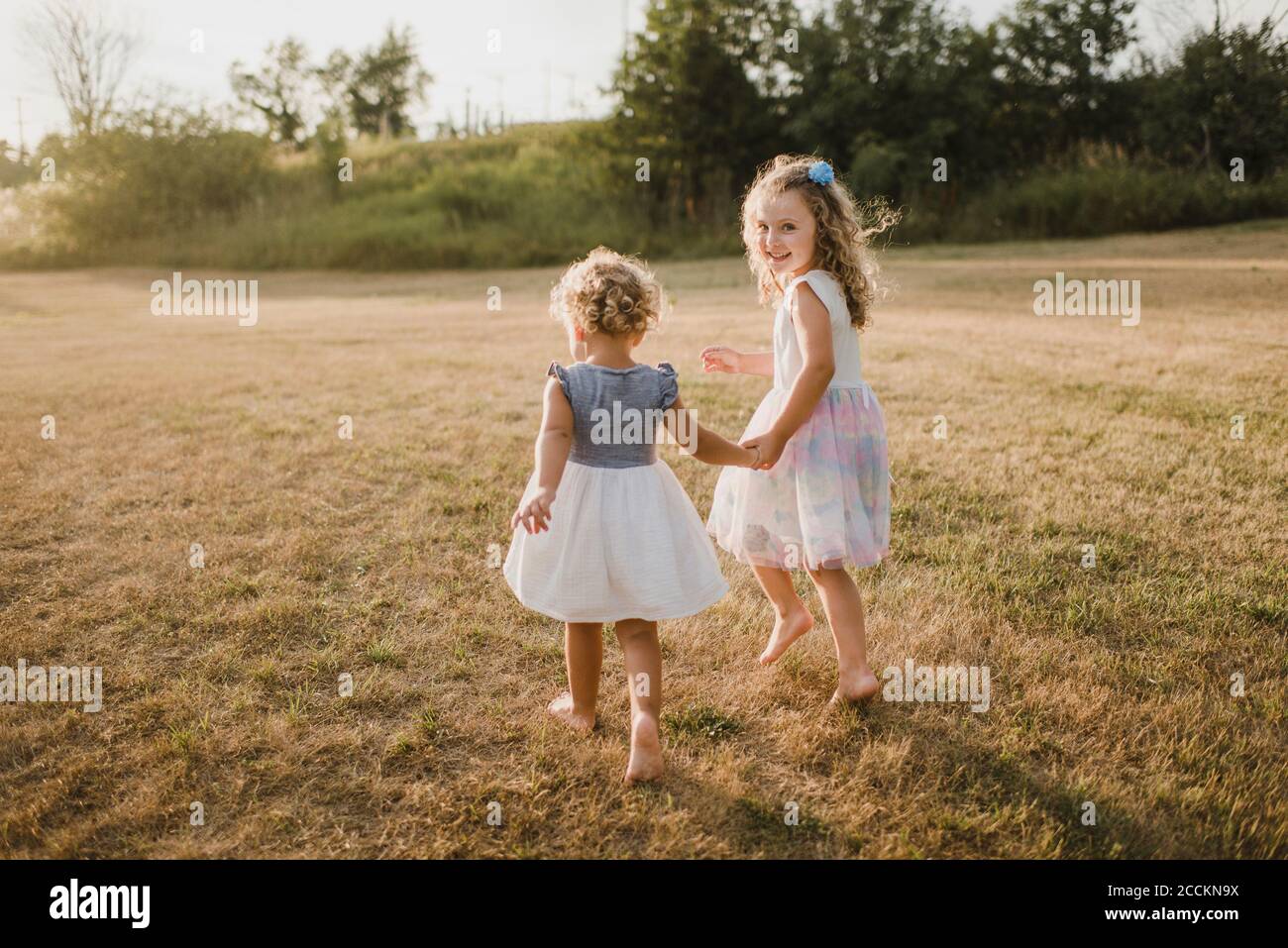 Girls walking hand in hand on a meadow Stock Photo