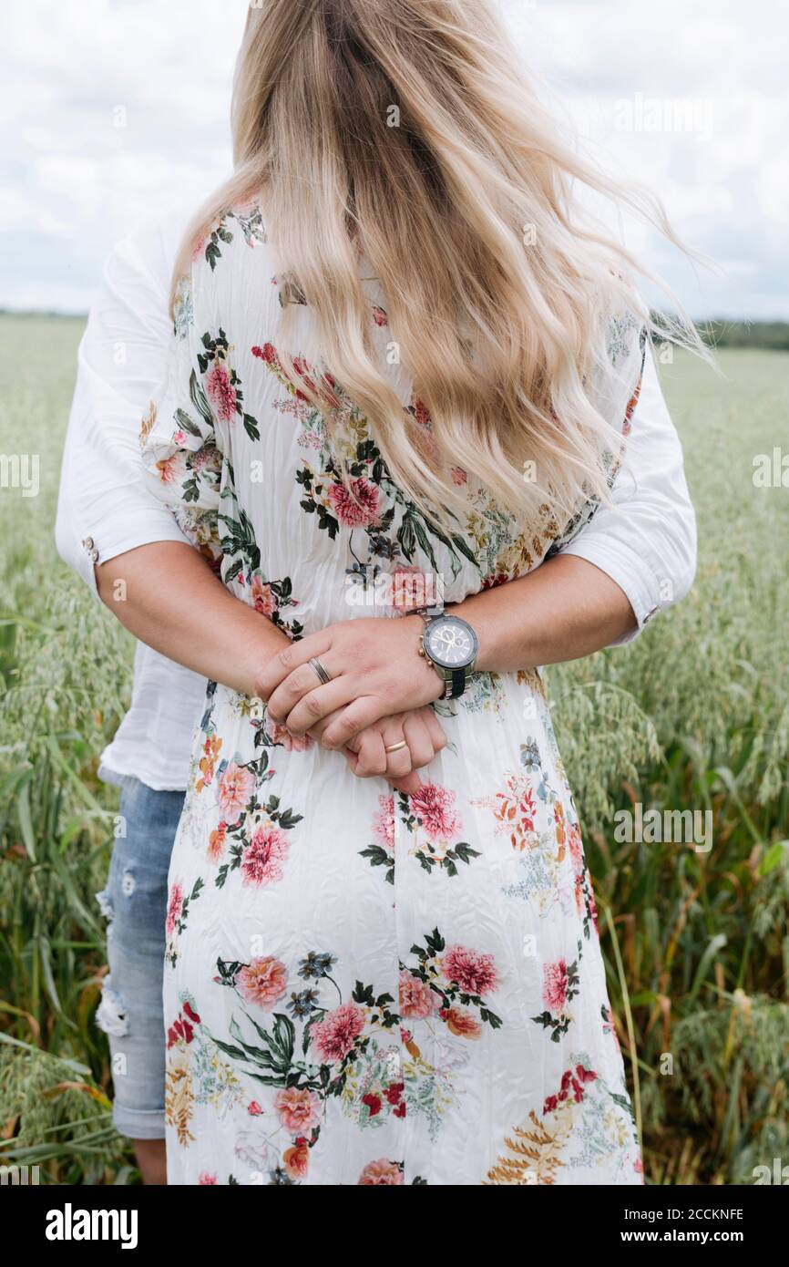 Loving husband embracing young woman while standing amidst oats field Stock Photo