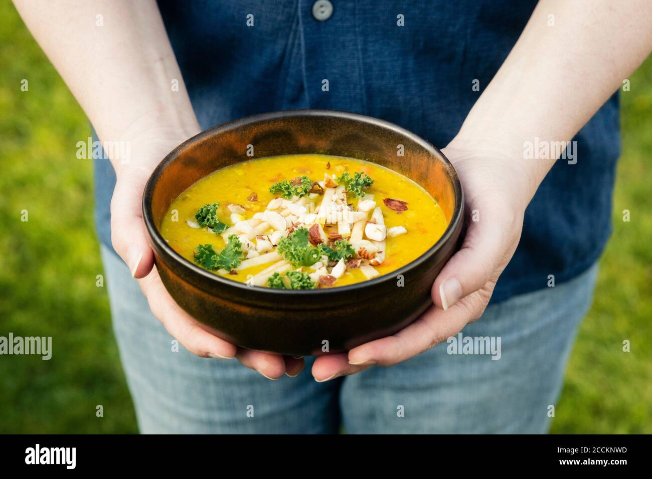 Mans hands holding bowl with dal of lentils, potatoes and vegetables Stock Photo