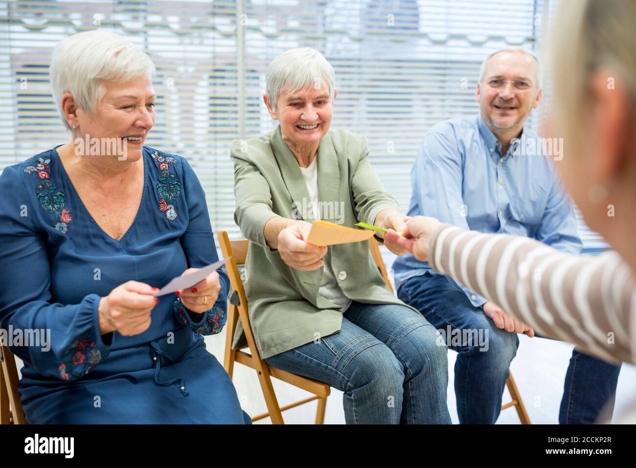 Seniors in retirement home attending group therapy using colorful paper cards Stock Photo