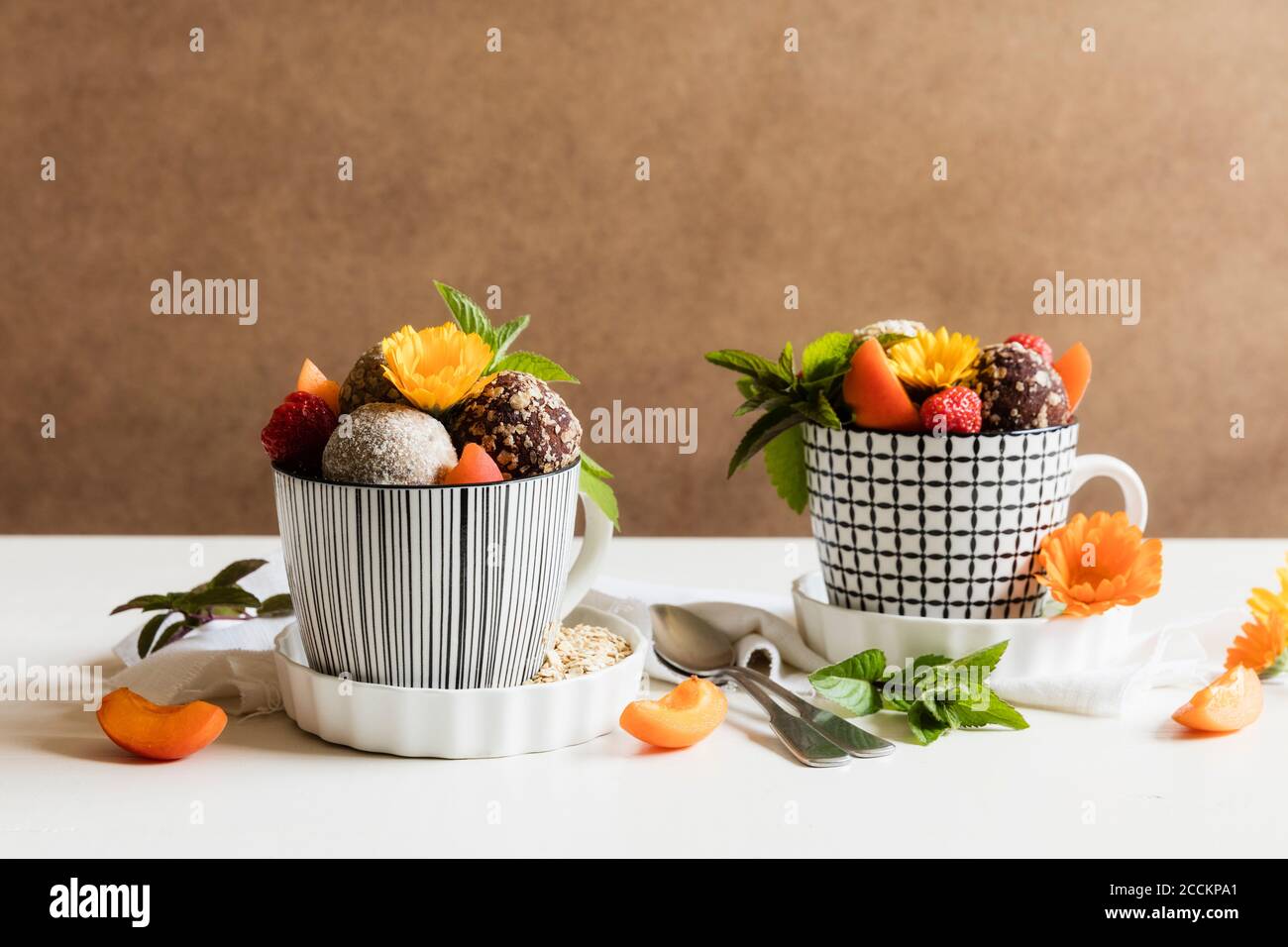 Dessert with energy balls (raw confectionery) and fresh fruits and flowers Stock Photo