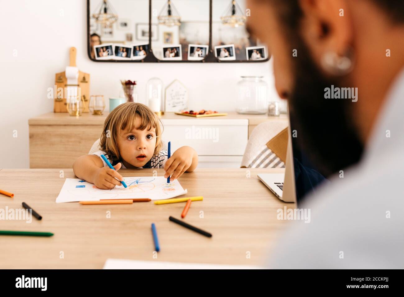 Cute girl looking at father while painting on paper in dining room Stock Photo