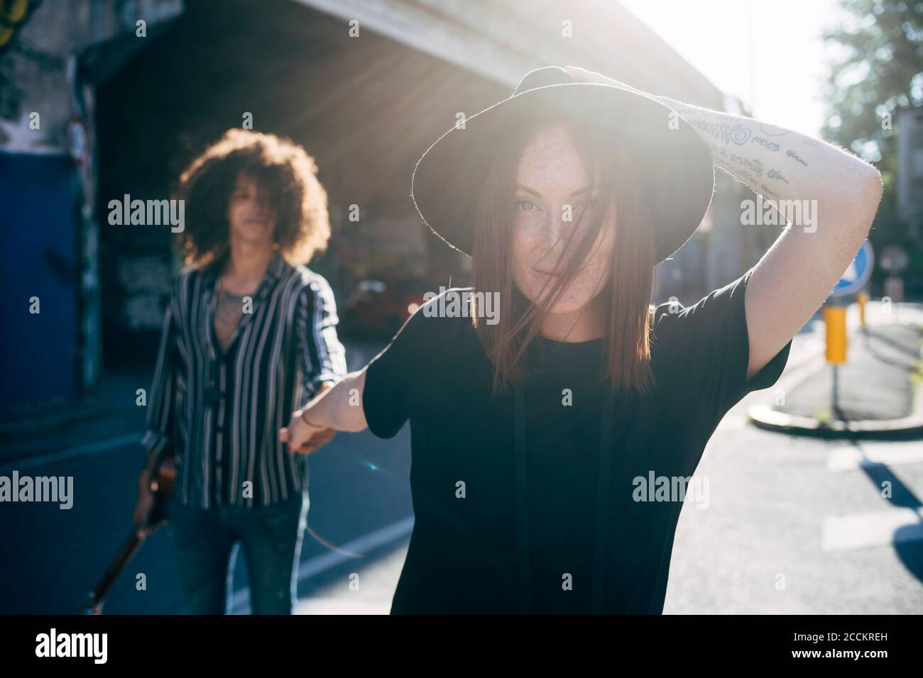 Young woman holding boyfriend's hand while walking on street in city Stock Photo