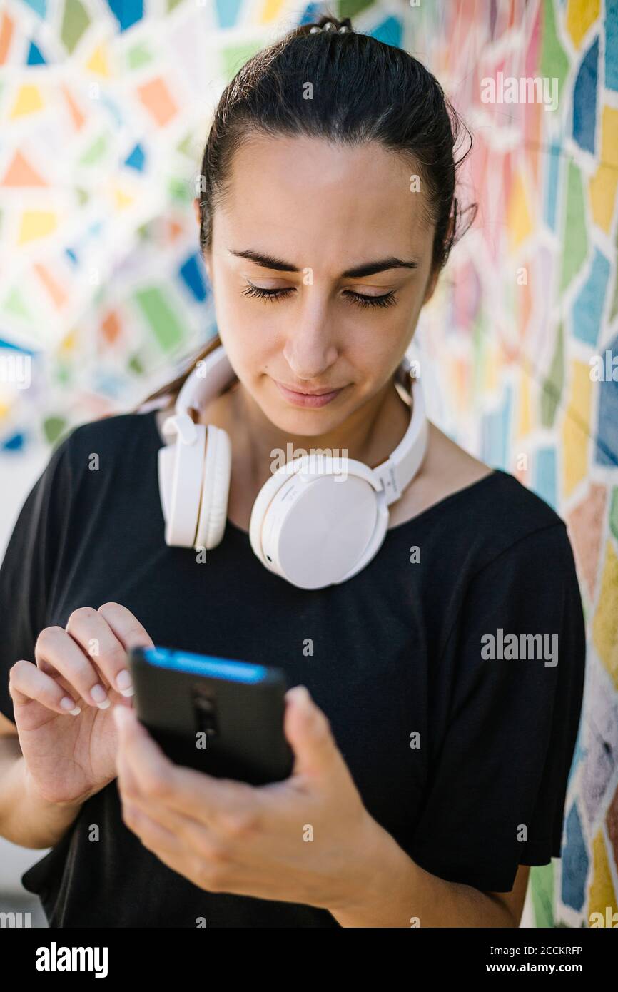 Portrait of woman using smartphone in front of colorful wall Stock Photo