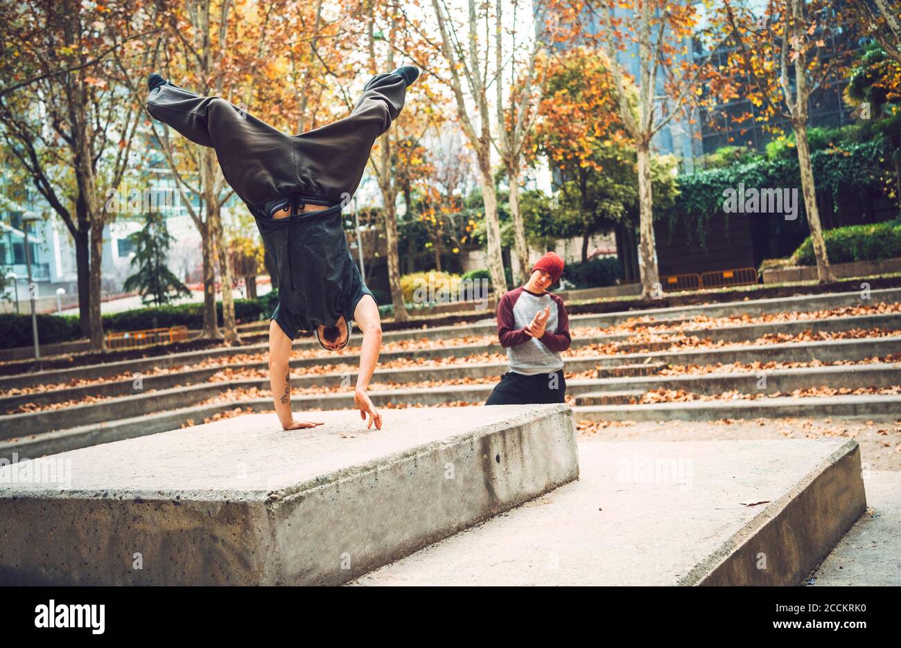 Young man performing handstand by friend in park Stock Photo