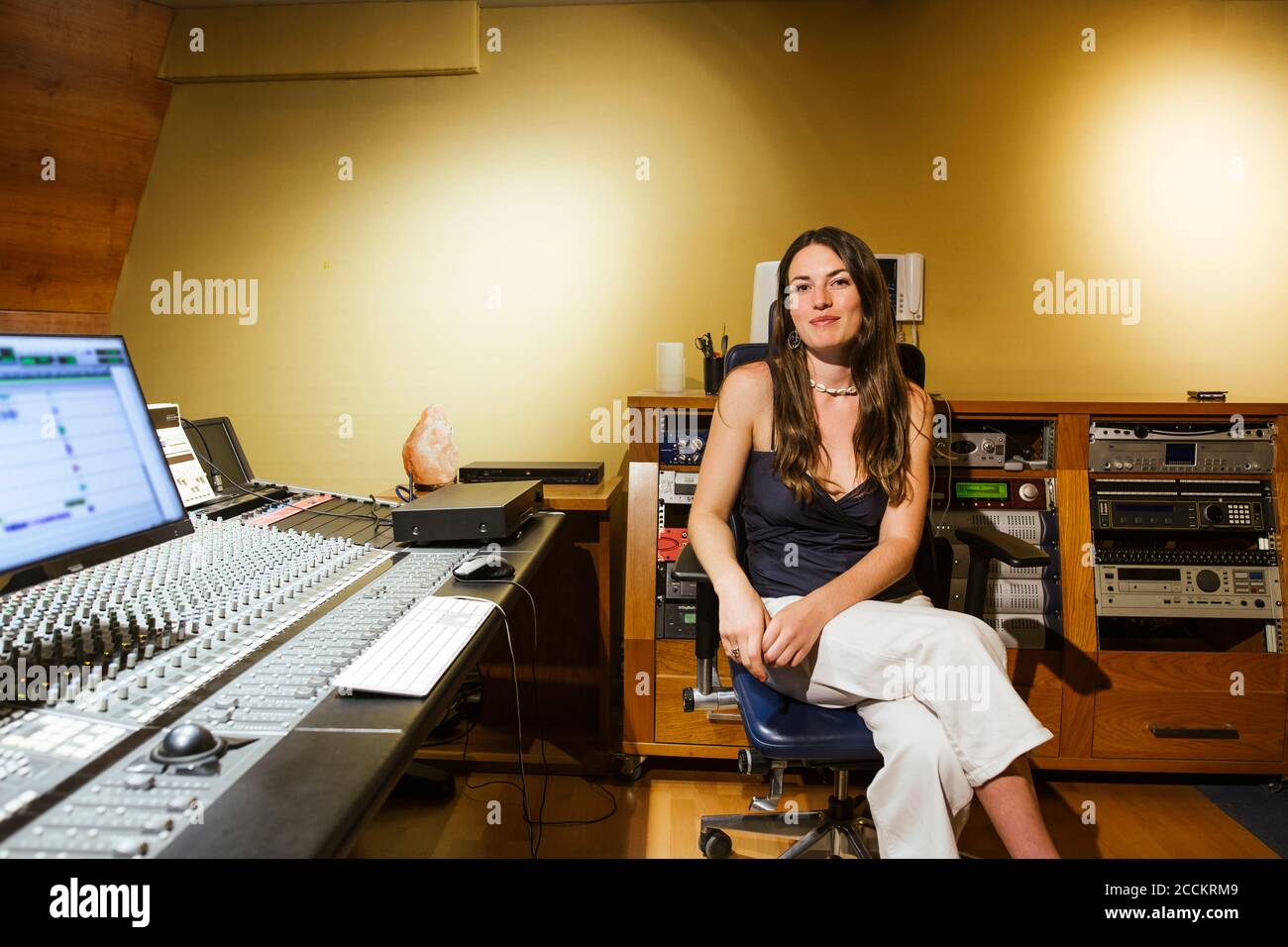 Smiling female singer sitting in recording studio Stock Photo