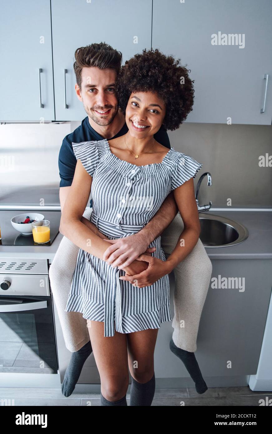 Romantic multi-ethnic couple embracing in kitchen of penthouse Stock Photo