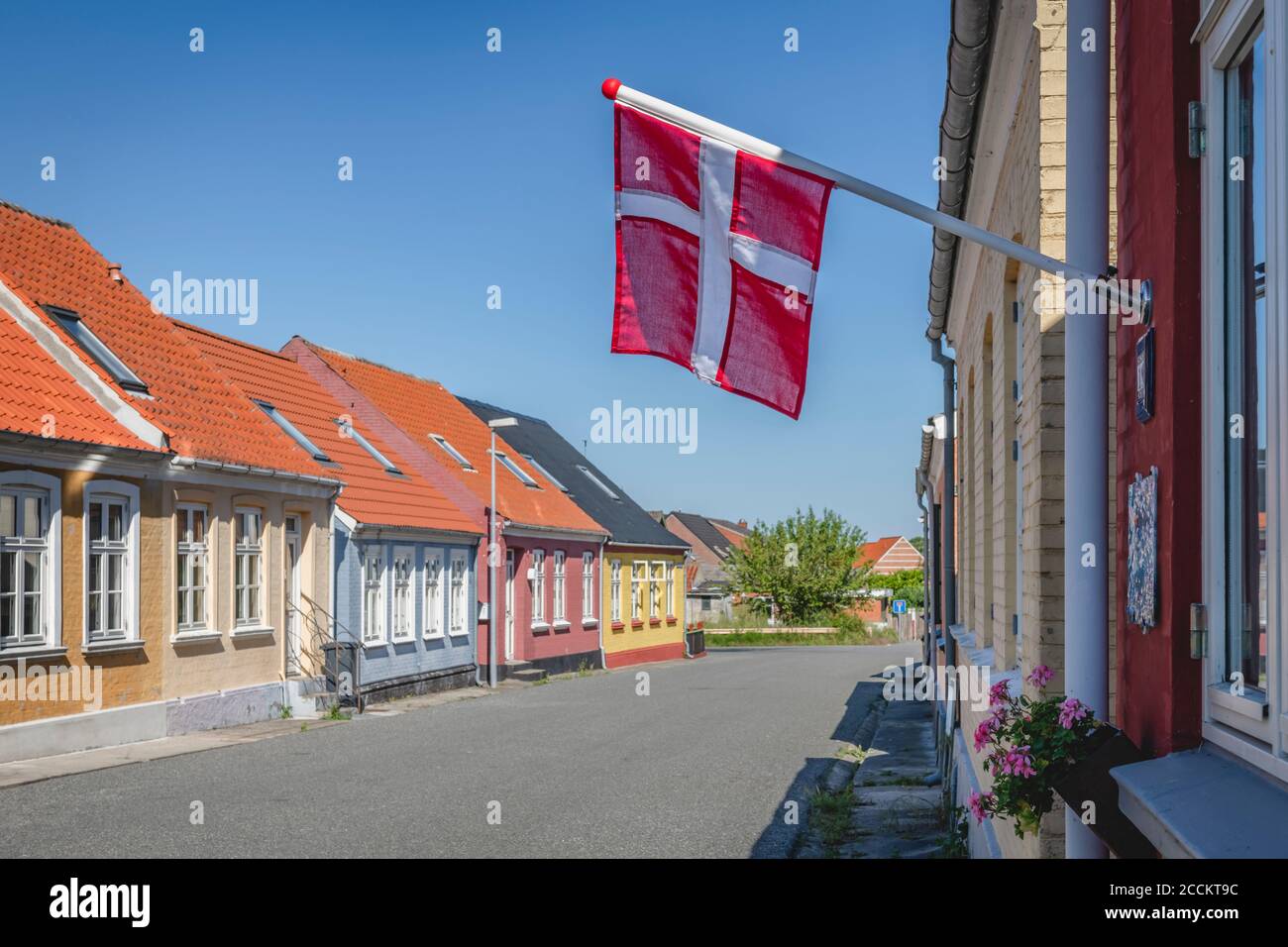 Denmark, Region of Southern Denmark, Marstal, Danish flag hanging over empty town street Stock Photo