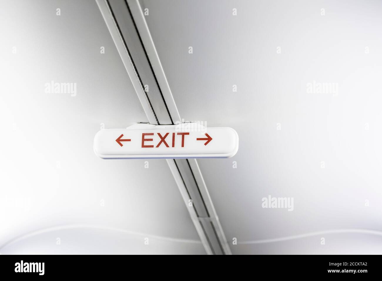 Exit sign on white airplane ceiling Stock Photo