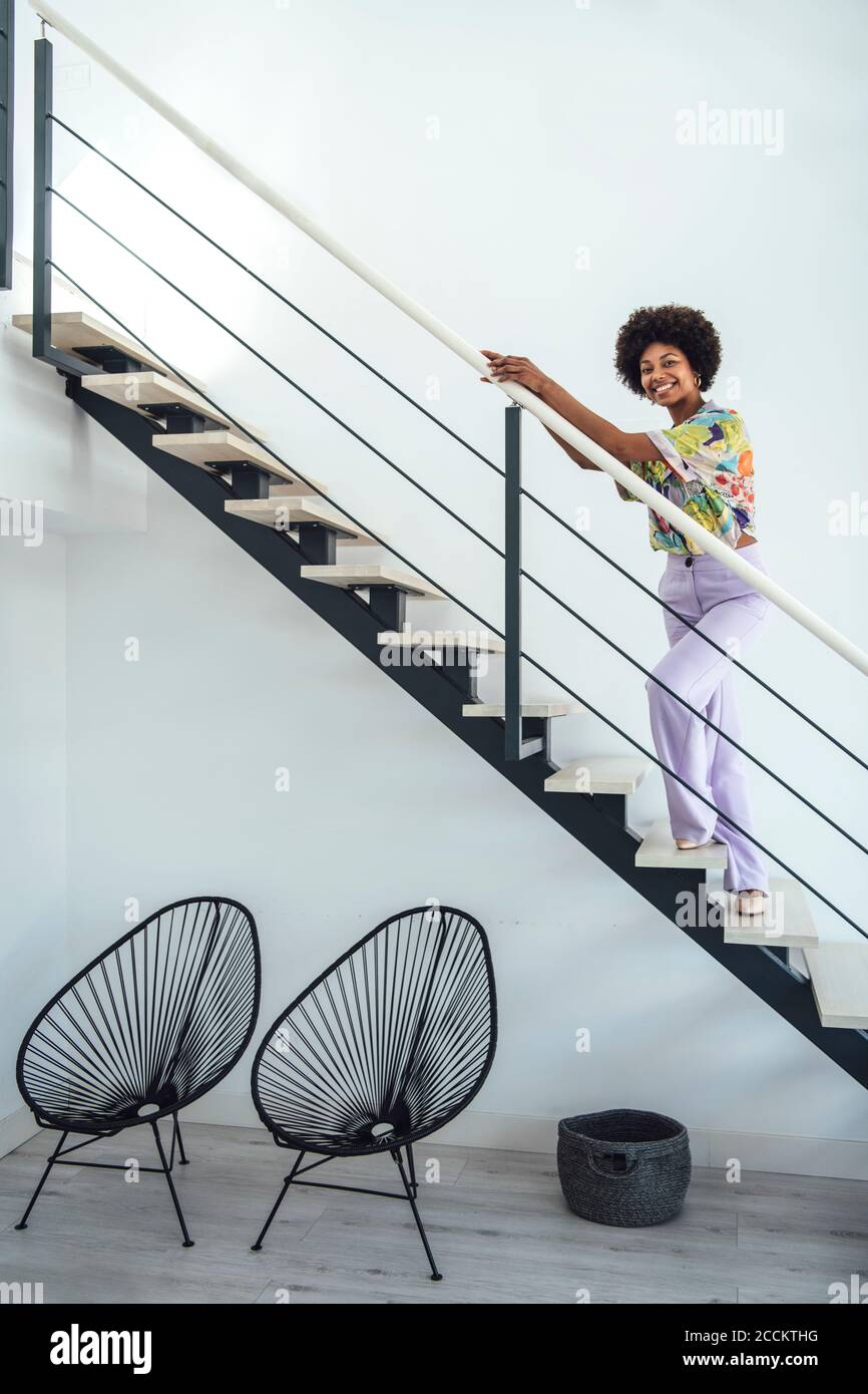 Happy woman standing on floating stairs in modern penthouse Stock Photo